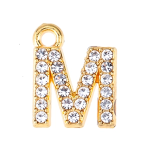 Macro view of gold-tone letter M pendant with clear rhinestones for jewelry making