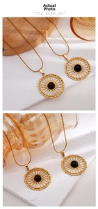 Detailed view of vintage gold hollow sunburst pendant with black gemstone and snake chain
