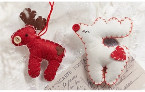 Macro shot of handmade wool felt reindeer Christmas tree ornaments on lace background