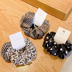 Close-up of leopard, polka dot and houndstooth scrunchies on light wood background