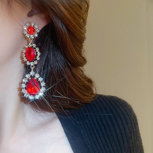 Gros plan d'une femme portant des boucles d'oreilles dorées avec pierres rouges et strass