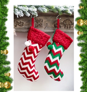 Close-up of festive knitted Christmas stockings with wave patterns and plush pom-poms