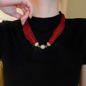 Detail of multi-strand red bead necklace with gold-plated diamond-encrusted sphere charms