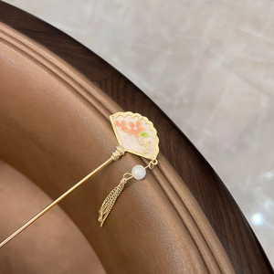 Macro detail of golden fan hair pin with enamel flowers and pearl tassel decoration