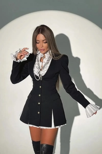 Detail of a black contrast shirt dress with white ruffles, gold buttons, and long sleeves