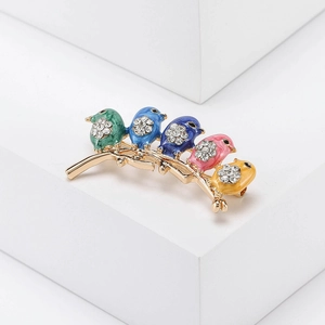 Detailed macro view of five colorful enamel birds perched on a gold branch brooch