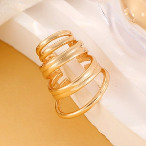 Macro shot of polished gold multi-layer spiral dragon ear cuff on marble base