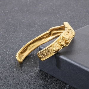 Dettaglio del rilievo del drago dorato e trama metallica sul bracciale in acciaio titanio