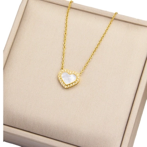 Collier cœur doré avec nacre blanche et pavé de cristaux sur un écrin à bijoux beige