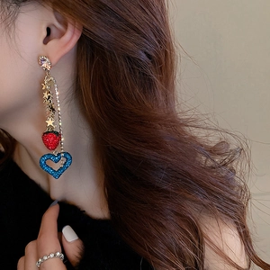 Detail of long tassel earrings featuring strawberry and heart charms on a model