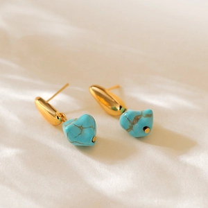 Macro detail of heart-shaped turquoise stone charms with polished 18K gold plated studs