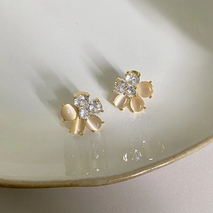 Macro detail of six-petal flower earrings with pink cat eye stones and clear diamonds