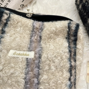 Detailopname van de zachte sherpa fleece make-up tas met blauwe strepen
