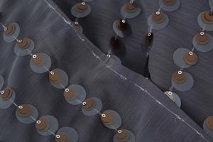 Detailed macro shot of bronze sequins on dark grey tulle fabric for a V-neck bodysuit