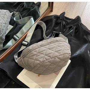 Detailed view of gray quilted crossbody bag with adjustable wide strap on a magazine