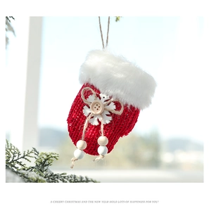 Close-up of red knitted glove Christmas ornament with white faux fur and wood snowflake