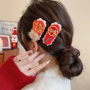 Close-up of red Chinese New Year hair clips with intricate embroidery and lucky charms