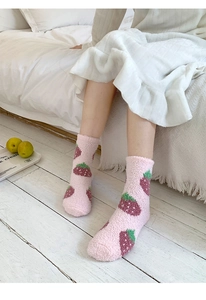 Close-up of thick coral fleece socks with pink strawberry pattern in a cozy home setting
