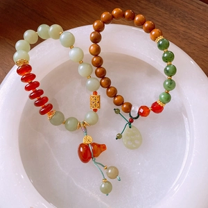 Detail of beaded bracelets featuring jade gourd and lotus pendants on a stone tray