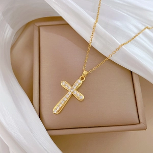Luxurious gold cross pendant necklace with sparkling crystals on a beige jewelry gift box
