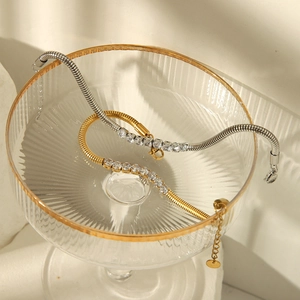 Detail of gold and silver snake chain bracelets with square zirconia inlay on glassware