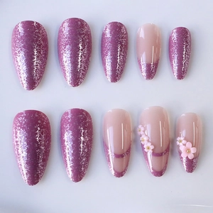 Pink and purple almond press-on nails with 3D floral accents and glitter French lines