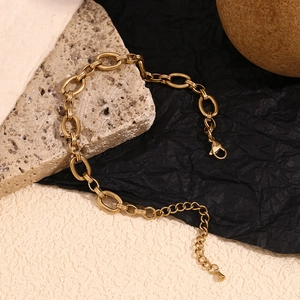 Detail view of a 14K gold-plated O-chain anklet with lobster clasp on a textured background