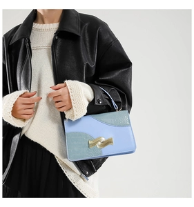 Detail of blue and green patchwork leather crossbody bag with golden metal clasp