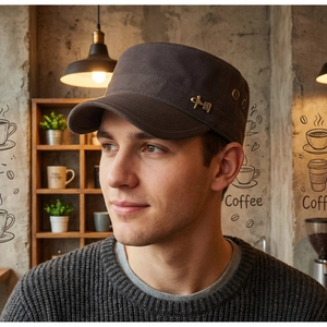 Detailed close-up of a charcoal flat top cadet cap with a gold emblem and ventilation eyelets