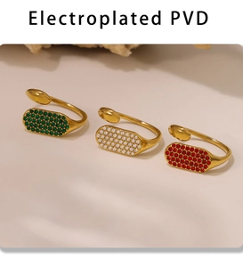 Détail de bagues ouvertes dorées PVD avec des pierres de zircon vert, blanc et rouge