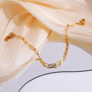 Detail of gold paperclip chain link bracelet featuring a lobster clasp and polished finish