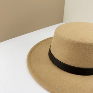 Close-up of a camel wool felt boater hat with a black leather belt buckle decoration