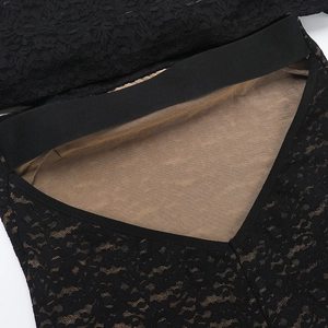 Detailed close-up of lace mesh fabric and elastic waistband with fine stitching on black jumpsuit
