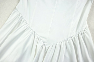Detail of white satin dress featuring intricate V-shaped stitching and pleated craftsmanship