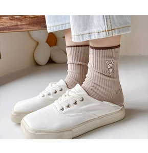 Close-up of khaki cotton crew socks with rabbit embroidery paired with white shoes