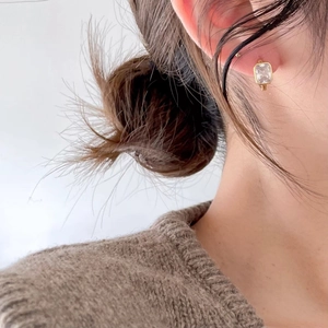 Close-up of a model wearing minimalist golden square zircon earrings in a warm setting