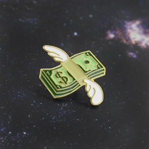 Macro shot of winged dollar money enamel pin with gold edging on blue starry background