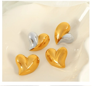 Détail de boucles d'oreilles cœur en acier titane avec finition miroir or et argent