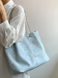 Light blue ice-flake print tote bag with silver chain strap shown on a model