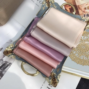 Solid color 100% mulberry silk long scarves in various shades on a decorative tray