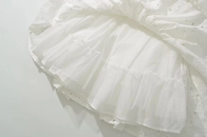 Détail de la broderie vintage française blanche et de l'ourlet de jupe en maille multicouche