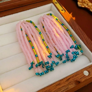 Gros plan de boucles d'oreilles à pompons en perles roses dans une boîte à bijoux