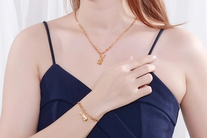 Detail of gold violin pendant necklace and matching bracelet set worn by a model