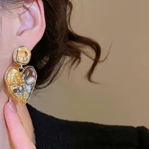 French vintage heart earrings with pearls and gold texture on a female model