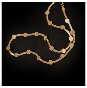 Close-up of golden snake chain necklace with polished round sequins on black background