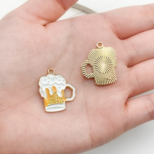 Detail showing the size of two beer mug charms in palm with enamel finish