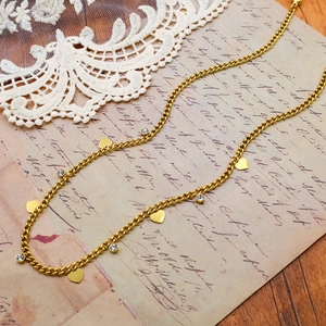 Gold chunky heart necklace with sparkling zircon charms on a vintage paper background