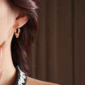Elegant gold double interlocking hoop earrings worn by a model in a side-view close-up shot