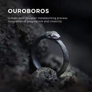 Artistic silver Ouroboros snake ring on black volcanic rock in a minimalist style