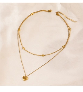 Gros plan d'un collier double épaisseur à pendentif cœur doré sur soie douce